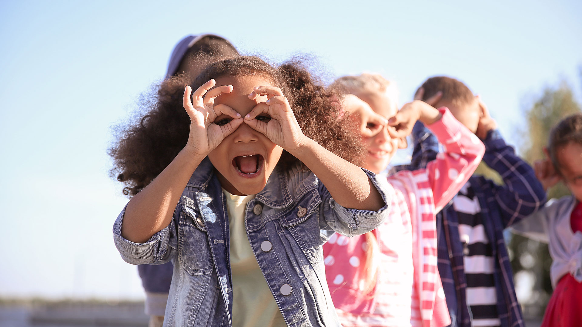 Kinder in einer Reihe machen Grimassen, blauer Himmel