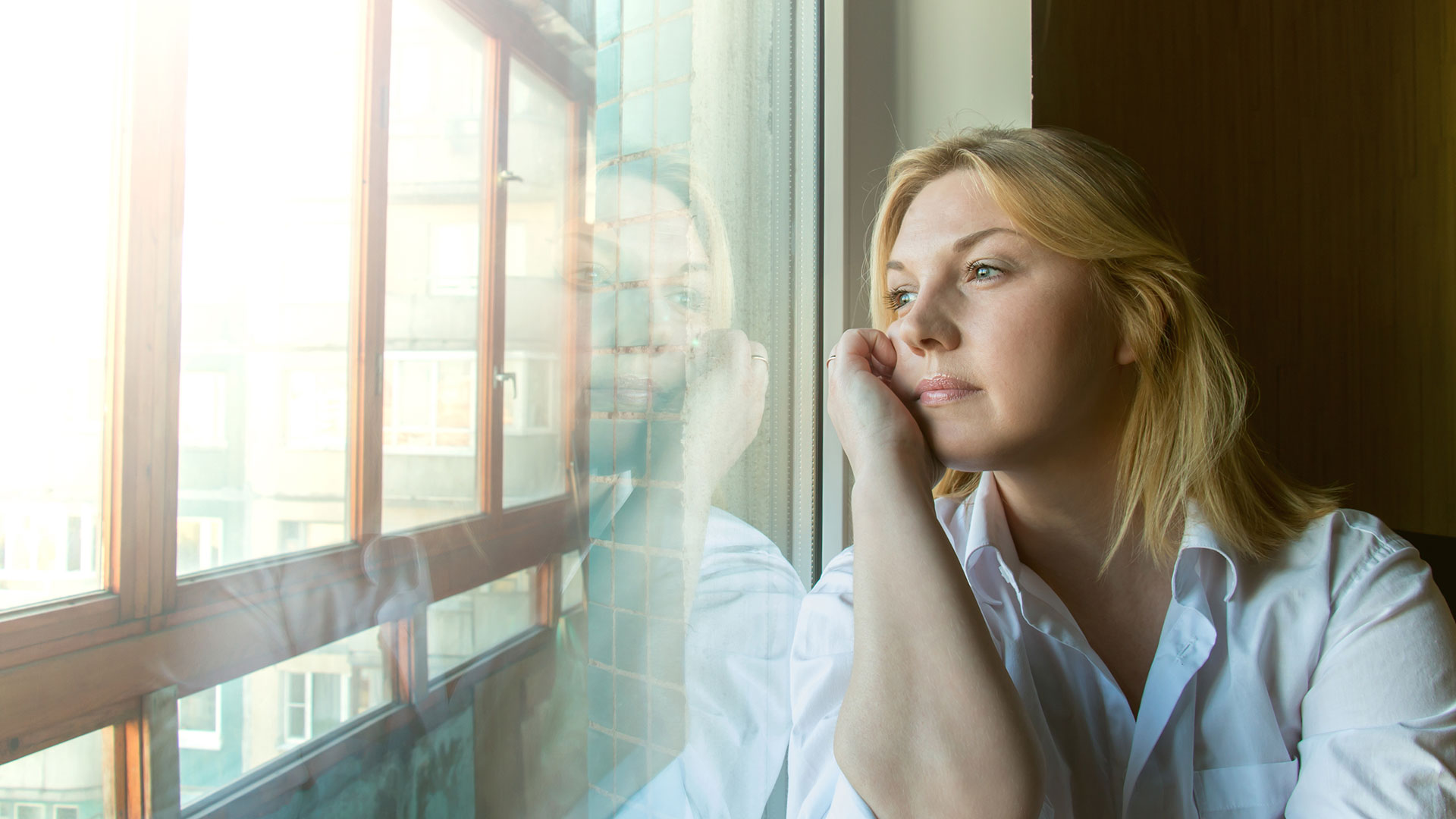 Junge Frau im Zug blickt nachdenklich aus dem Fenster