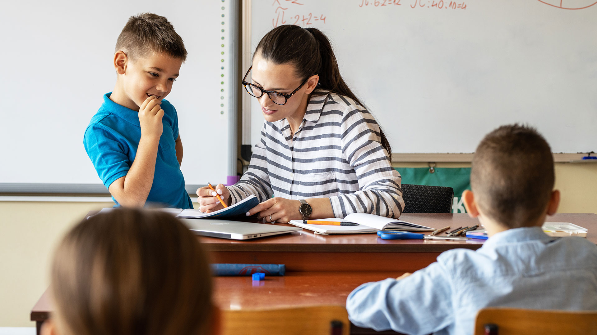Eine Frau am Lehrerbild erklärt einem Kind etwas