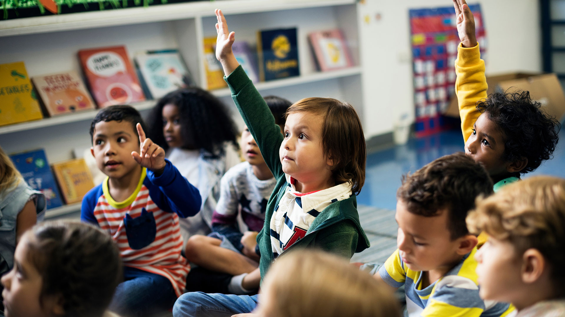 Kinder sitzen auf dem Boden, ein Kind in der Mitte zeigt auf