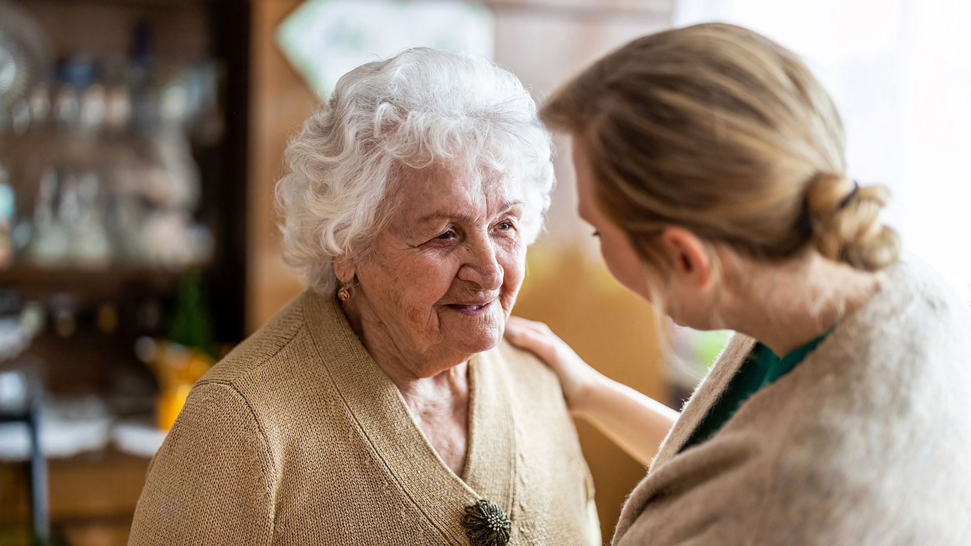 Eine ältere Dame und eine jüngere Frau stehen sich nah gegenüber