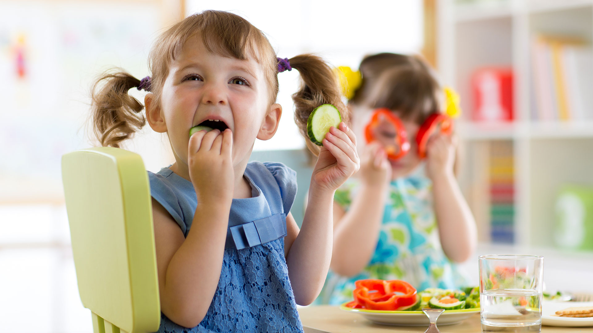Zwei Mädchen essen rohes Gemüse im Kindergarten.