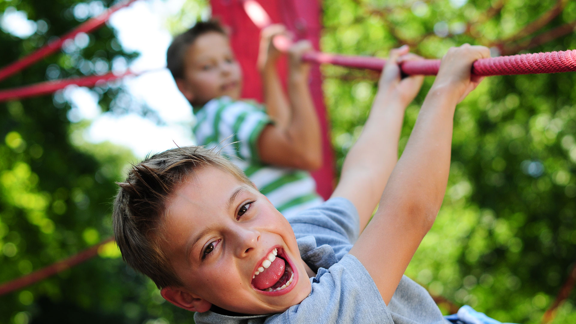 Zwei Jungs klettern auf einem Klettergerüst aus Seilen.