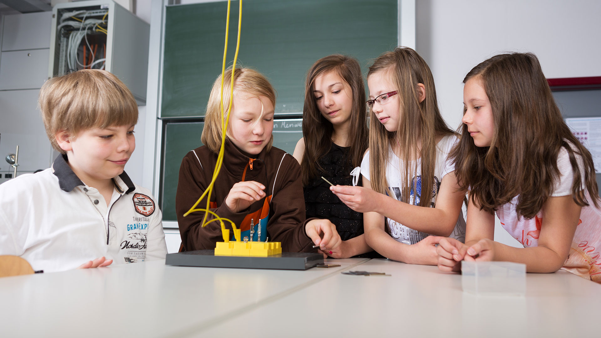 Eine Gruppe von Grundschülerinnen und Grundschüler machen ein Experiment mit einem Stromkreis.
