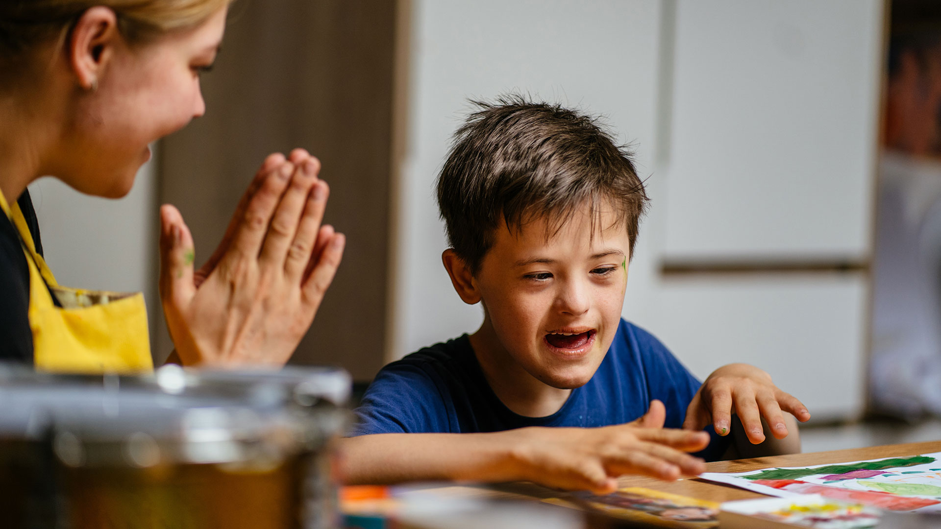 Lehrerin klatscht in die Hände, um ein Kind mit Behinderung zu motivieren