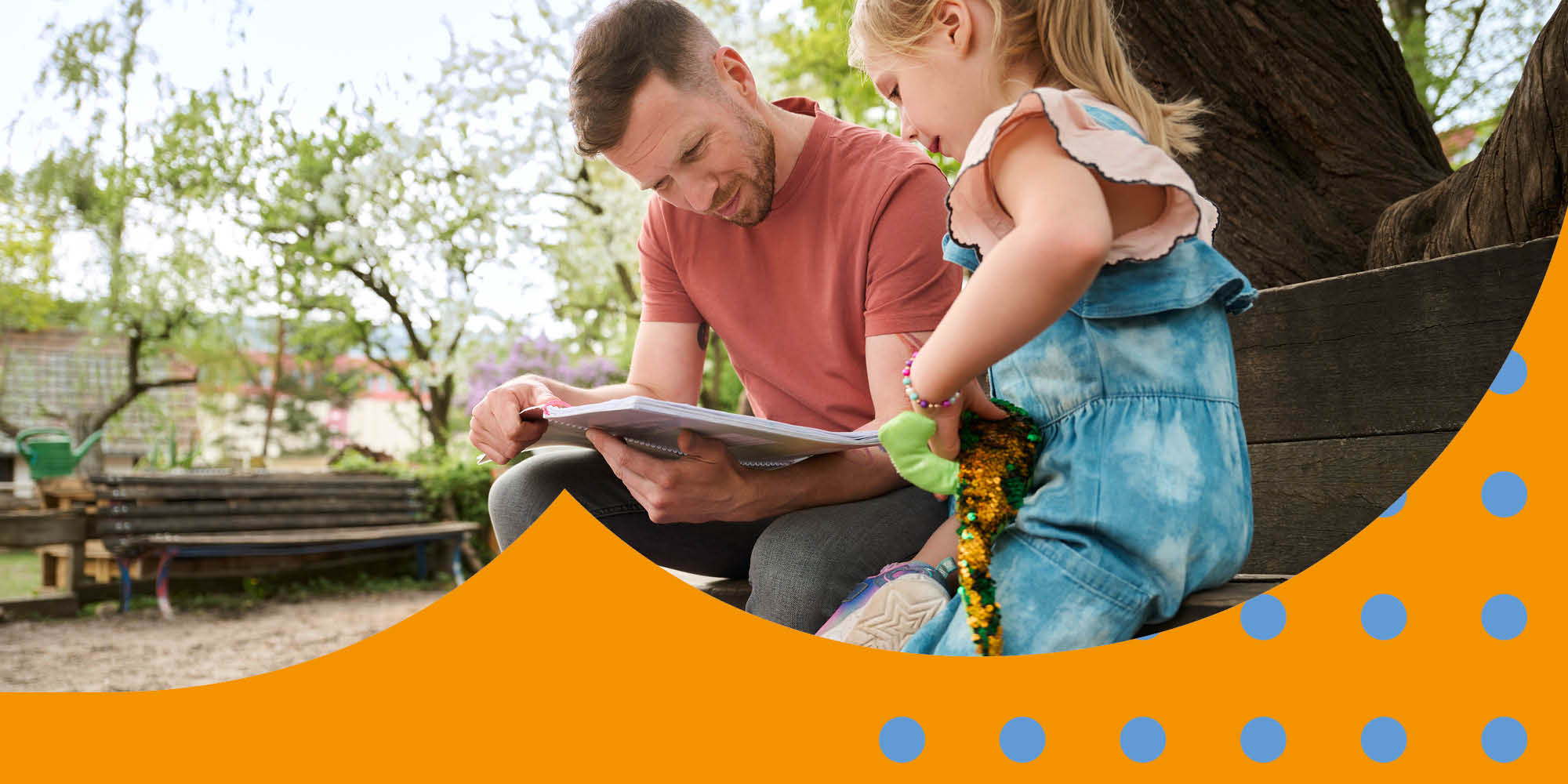 Ein Vater sitzt mit seiner Tochter auf einer Bank auf einem Spielplatz und kontrolliert die Hausaufgaben.