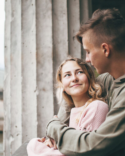 Junges Mädchen und Junge halten sich im Arm, dahinter eine Stadt