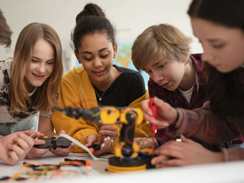 Eine Gruppe Kinder baut im Unterricht an einem fernsteuerbaren Roboter.