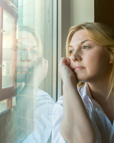 Junge Frau im Zug blickt nachdenklich aus dem Fenster