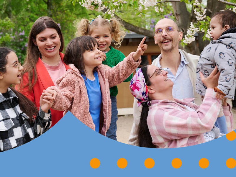Eine gemischte Gruppe Eltern steht mit ihren Kindern auf einem Spielplatz.