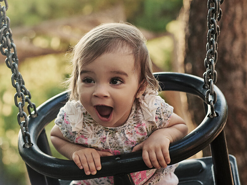 Kampagnenmotiv Familienservicebüros Jugendämter Berlin: Ein Kind sitzt auf der Schaukel. Text auf dem Bild „Schwung fürs Familienleben, Familienservicebüros: Unterstützung. Vor Ort. Für Familien“