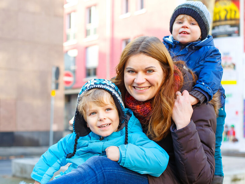 Eine Mutter ist im Winter mit ihren beiden Kindern in Berlin unterwegs.