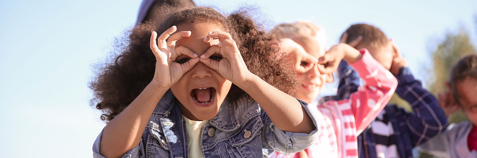 Kinder in einer Reihe machen Grimassen, blauer Himmel