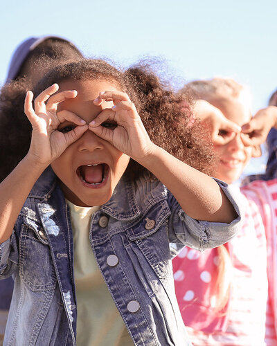 Kinder in einer Reihe machen Grimassen, blauer Himmel