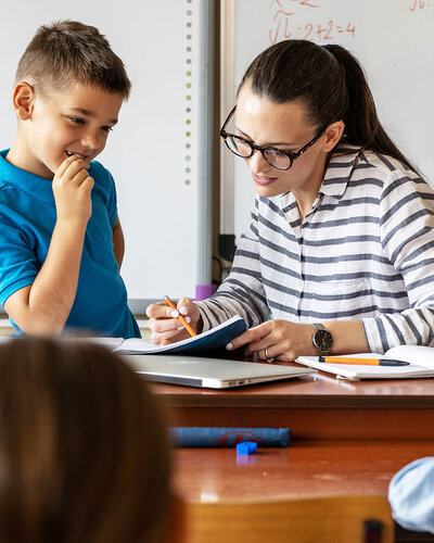 Eine Frau am Lehrerbild erklärt einem Kind etwas