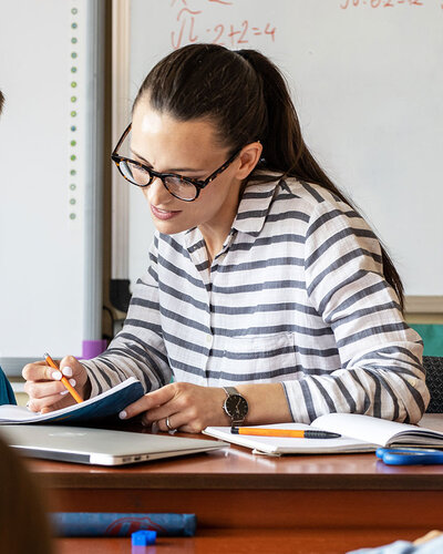 Eine Frau am Lehrerbild erklärt einem Kind etwas