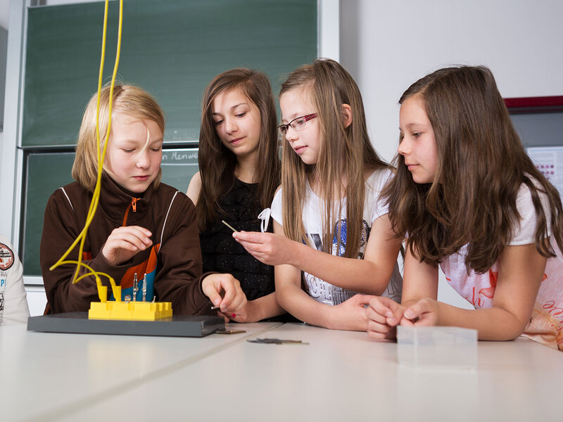 Eine Gruppe von Grundschülerinnen und Grundschüler machen ein Experiment mit einem Stromkreis.