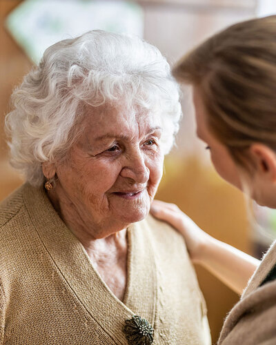 Eine ältere Dame und eine jüngere Frau stehen sich nah gegenüber