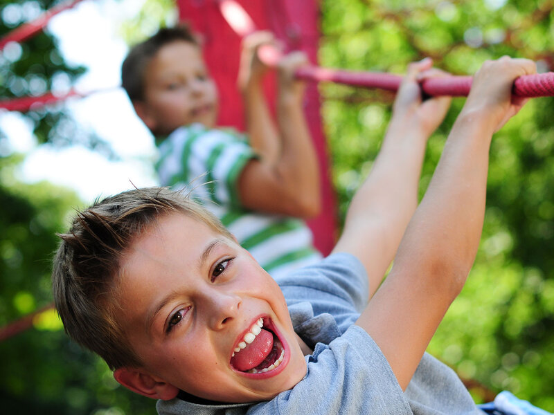 Zwei Jungs klettern auf einem Klettergerüst aus Seilen.