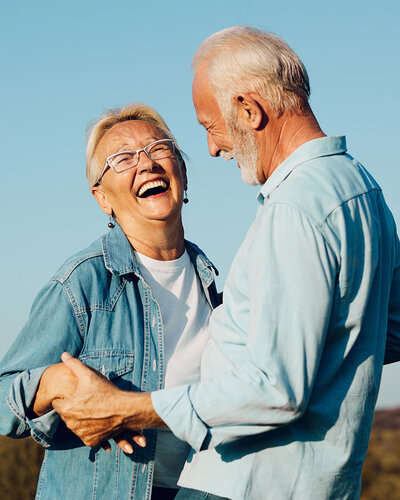 Ältere Frau und älterer Mann lachen glücklich, in der Natur