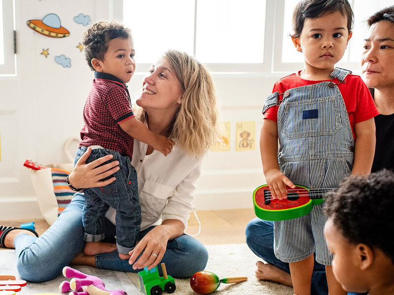 Eltern spielen mit ihren Kindern in einer Spielgruppe.